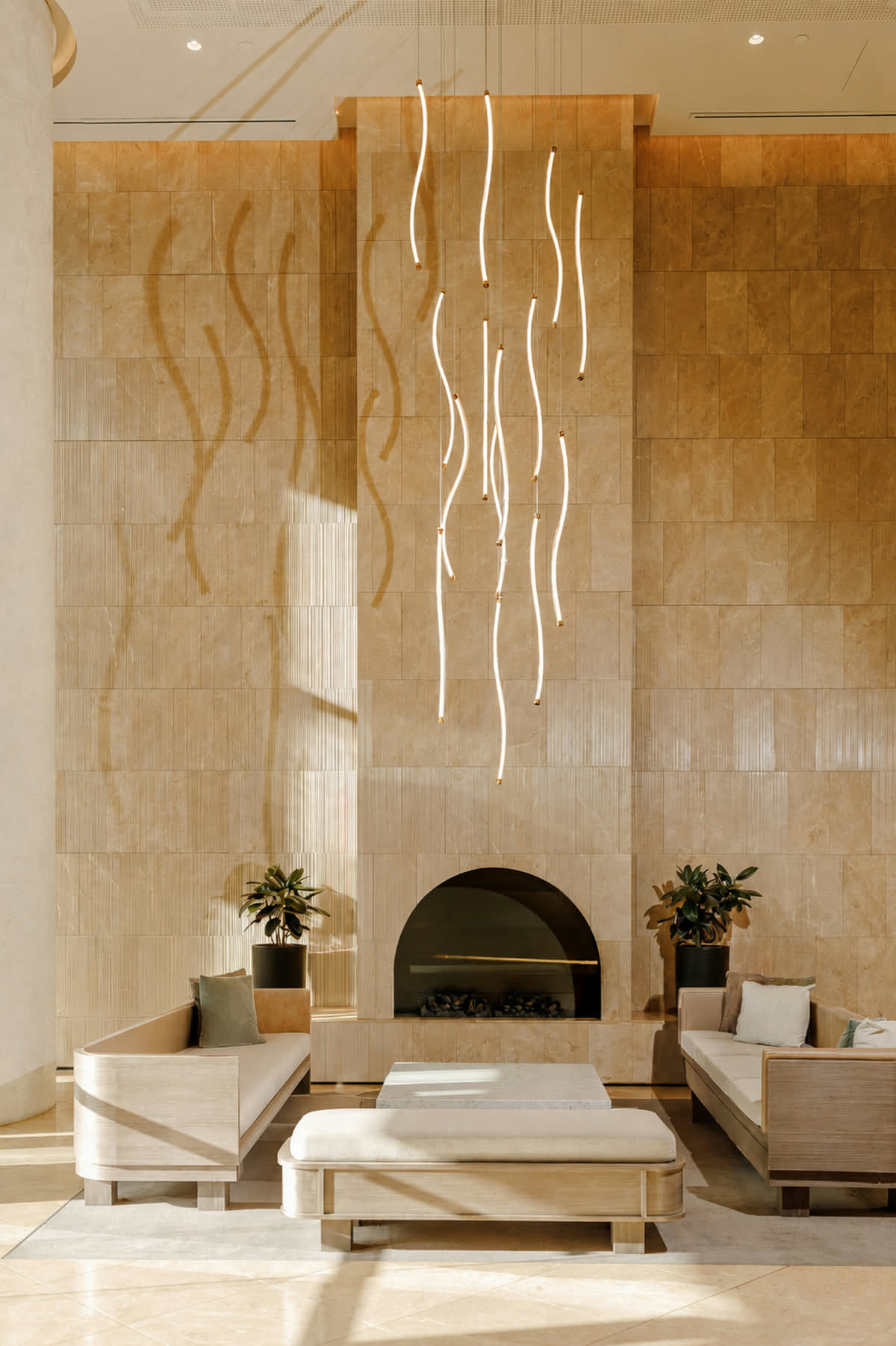 Sunlit hotel lobby with a stone wall, hanging light tubes and an arched fireplace, as a standard-range JPEG